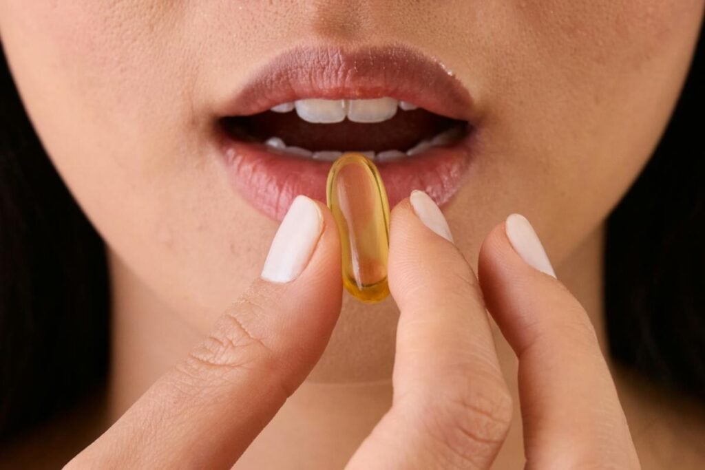 woman placing a vitamin or supplement in her mouth