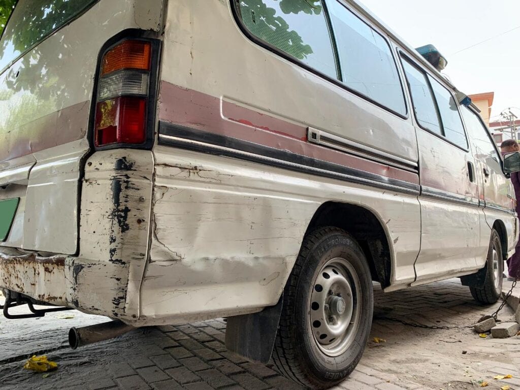 A white van with visible scratches, dents, and rust, highlighting the impact of neglect and improper car care.