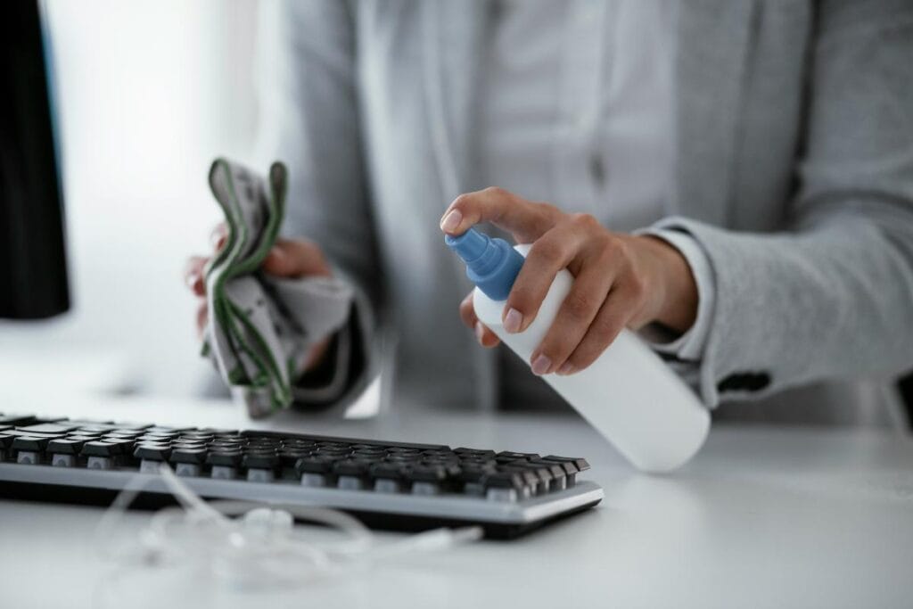 woman spraying disinfectant on a keyboard at the office