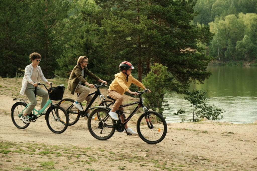 Family riding bikes along a scenic lakeside trail, enjoying outdoor exercise and bonding time as part of a balanced health routine.