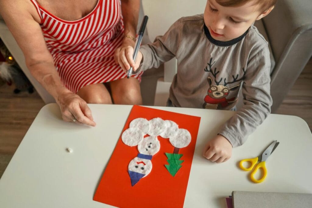 grandma helping little boy make a snowman christmas card