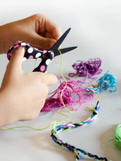 child cutting materials to make friendship bracelets
