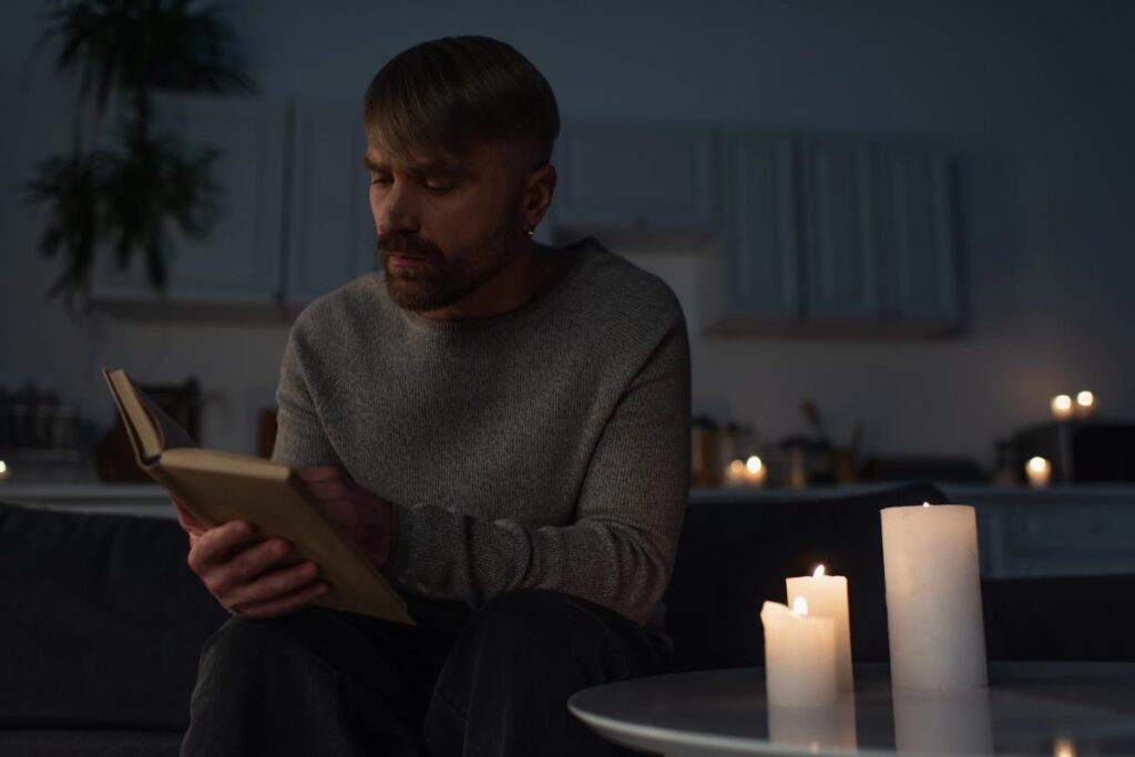 man reading a book surrounded by lit candles during a power outage