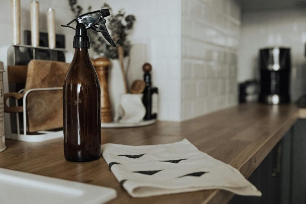 An eco-friendly multi-surface spray bottle on a tidy wooden kitchen countertop, perfect for quick cleaning and sanitizing busy home spaces.