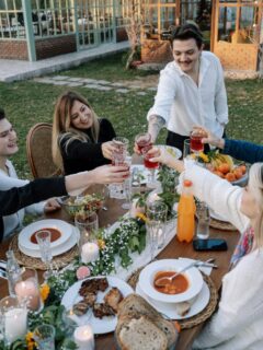 Group of friends raising glasses in a cheerful toast around a beautifully set outdoor table.