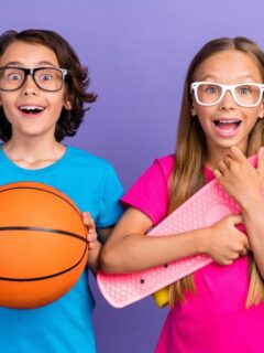 Two excited kids wearing glasses, one holding a basketball and the other holding a pink skateboard, standing against a purple background.