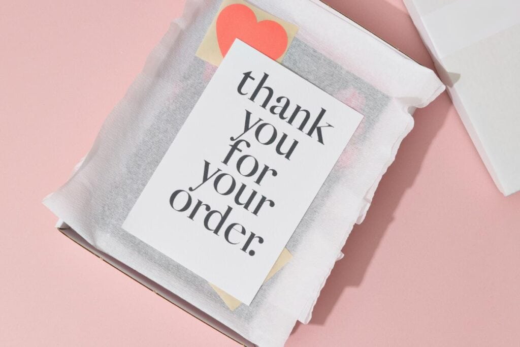 Thank you card included in Etsy order packaging with white tissue paper and heart sticker on pink background