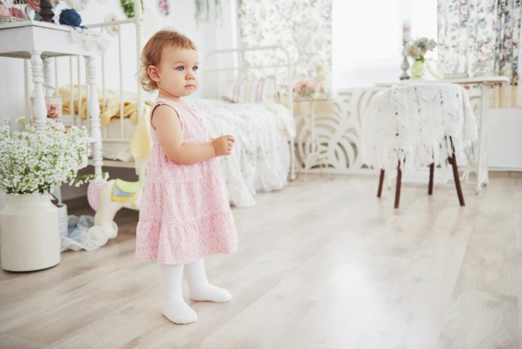 a toddler girl in a pink dress in a playroom