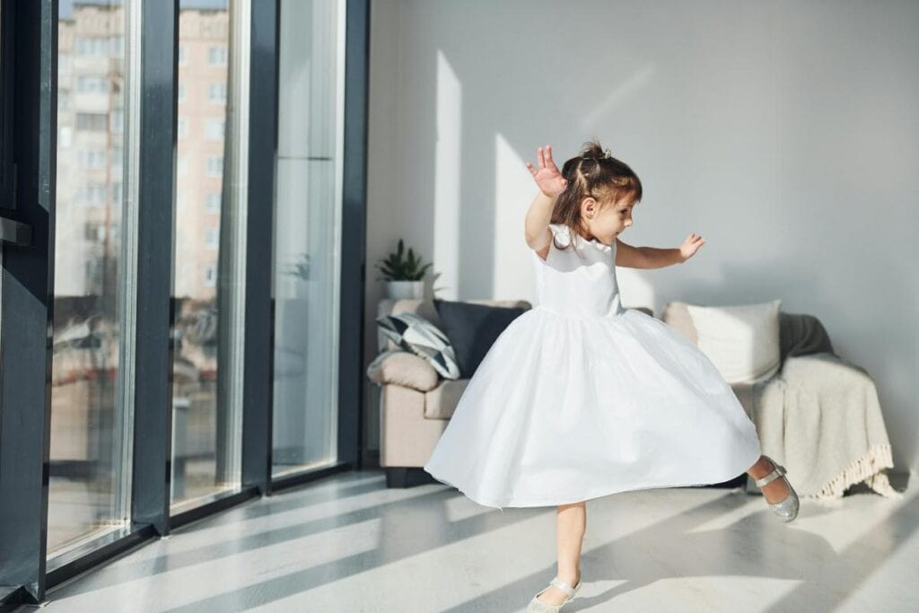 toddler girl in a white dress dancing