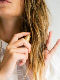 blonde woman applying serum to ends of hair