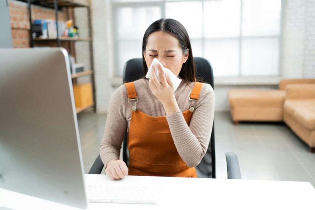 woman sneezing at her desk