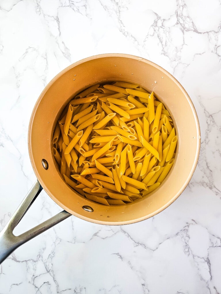 Penne cooking in a saucepan of salted water for jalapeño popper chicken casserole.