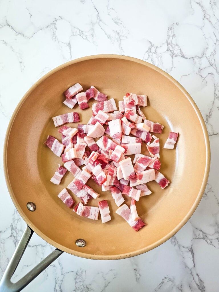 Chopped thick-cut bacon in a skillet, ready to crisp for casserole topping.