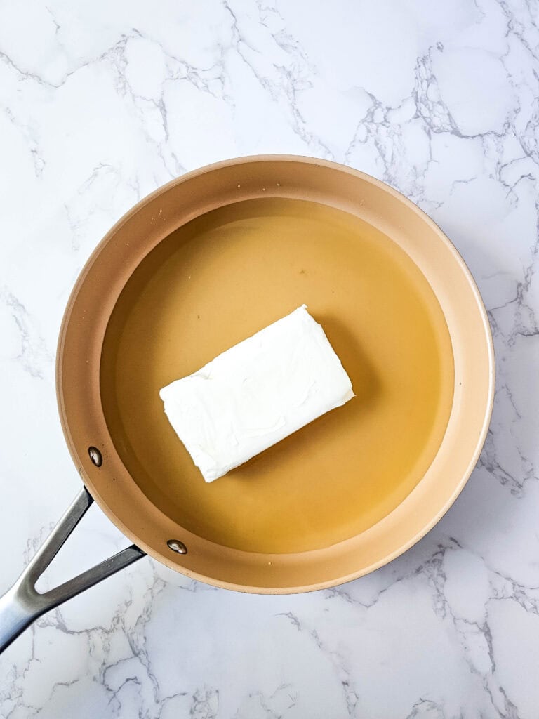 Chicken broth added to cream cheese in the skillet; melt over medium-low heat.