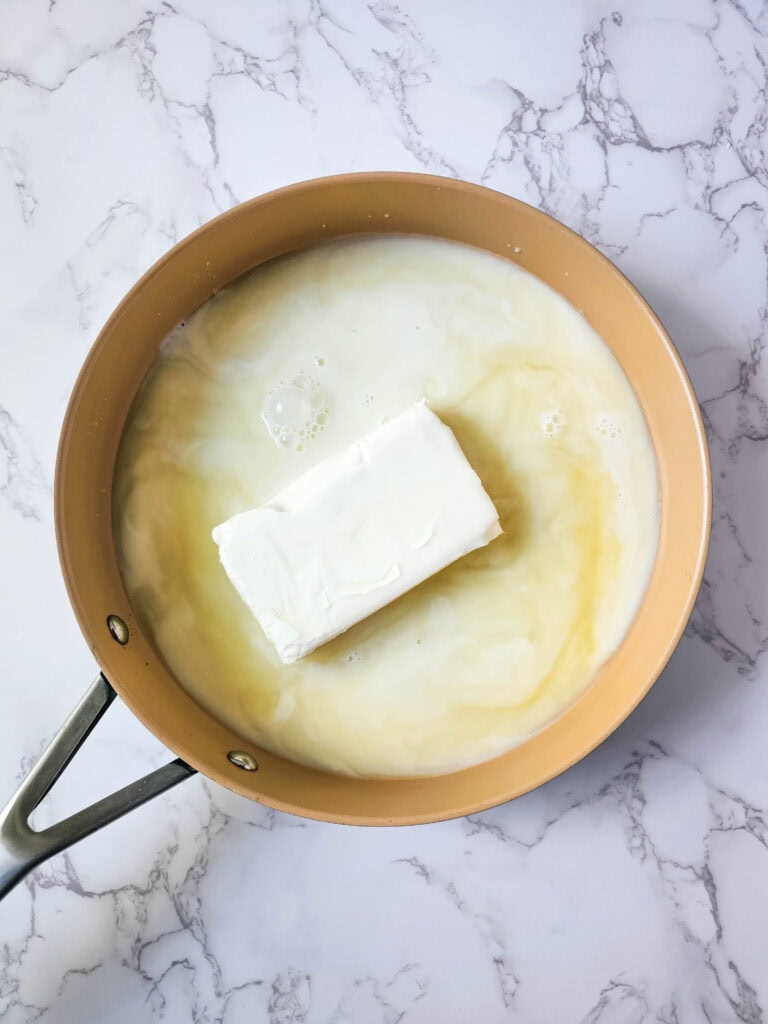 Milk poured into the skillet with broth and cream cheese to make the sauce.