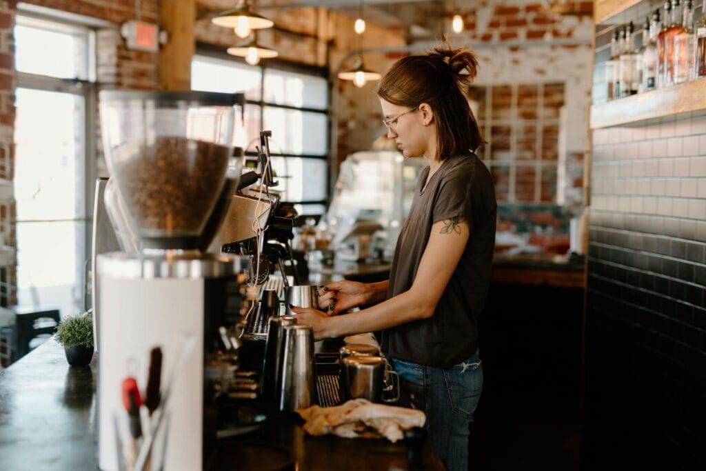 A barista making espresso with freshly ground specialty coffee beans at a café, highlighting artisanal brewing and small-batch roasters.