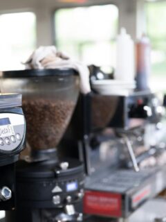 Close-up of coffee grinders and espresso machines in a specialty coffee shop, showcasing fresh roasted beans and quality brewing equipment.