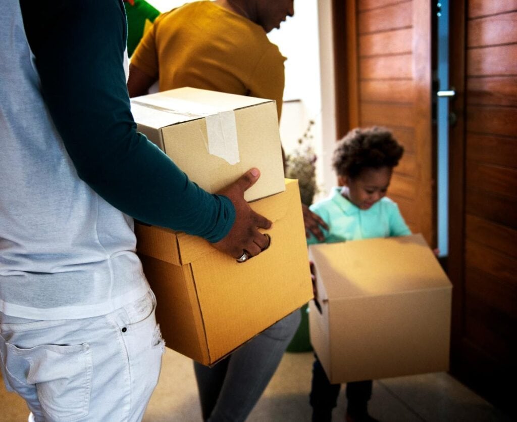 family carrying boxes into their new home