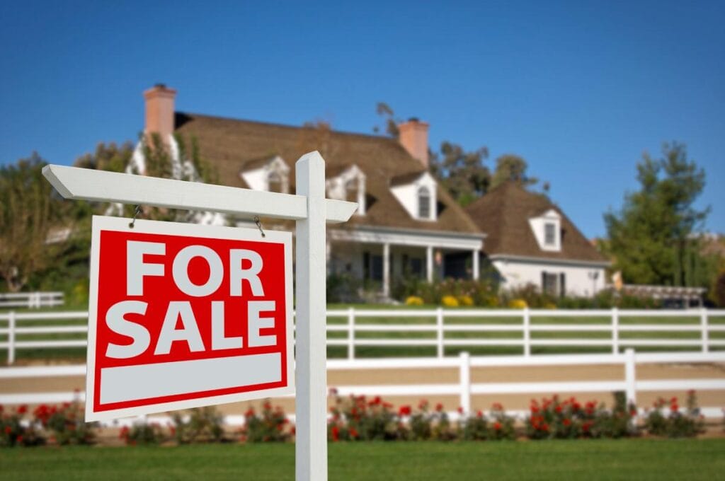 ed for sale sign in front of suburban house with white fence, representing homes listed on the Minneapolis–St. Paul real estate market.