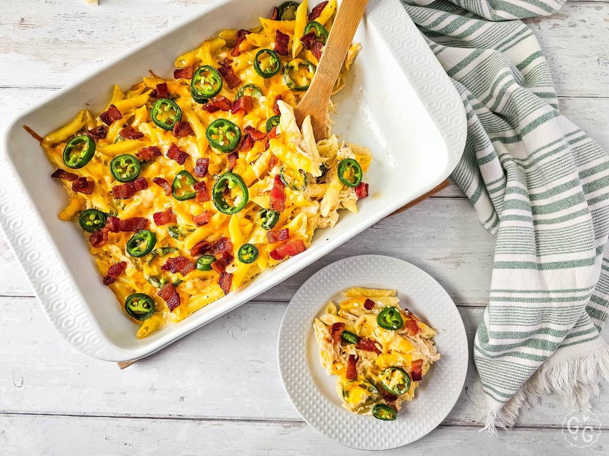 Overhead of jalapeño popper chicken casserole in a baking dish with a plated serving beside it.