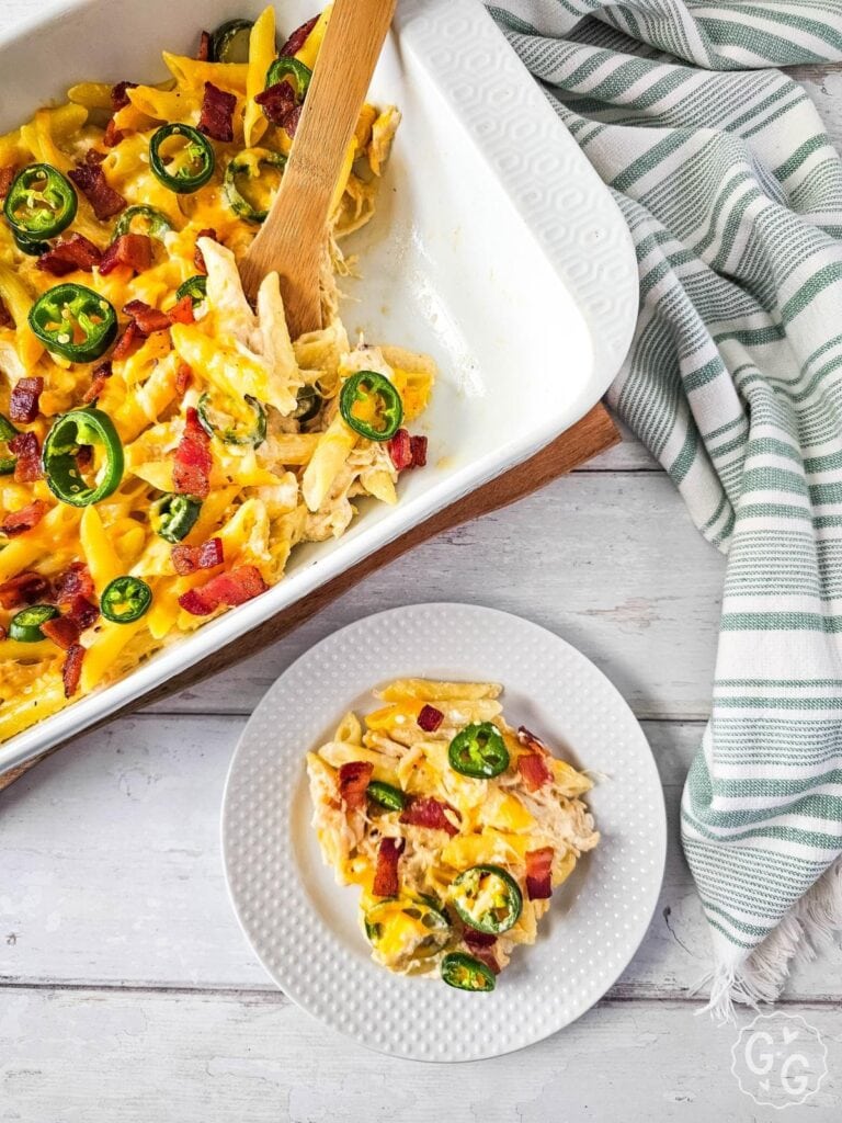 Serving of jalapeño popper chicken casserole with bacon and jalapeño slices on a white plate.