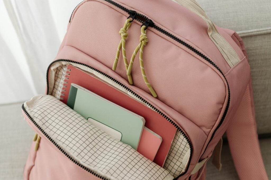 Open pink backpack neatly packed with colorful notebooks and folders, showing an organized school supplies setup.