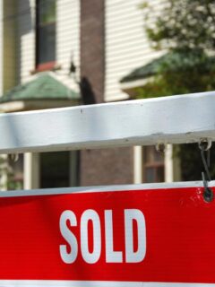 Red sold sign in front of house, symbolizing a successful home sale in the Minneapolis–St. Paul housing market.