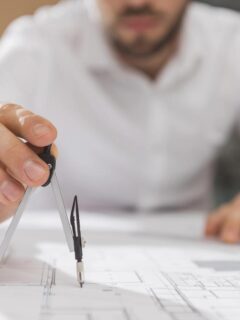 Architect using a compass to measure details on a set of building blueprints.