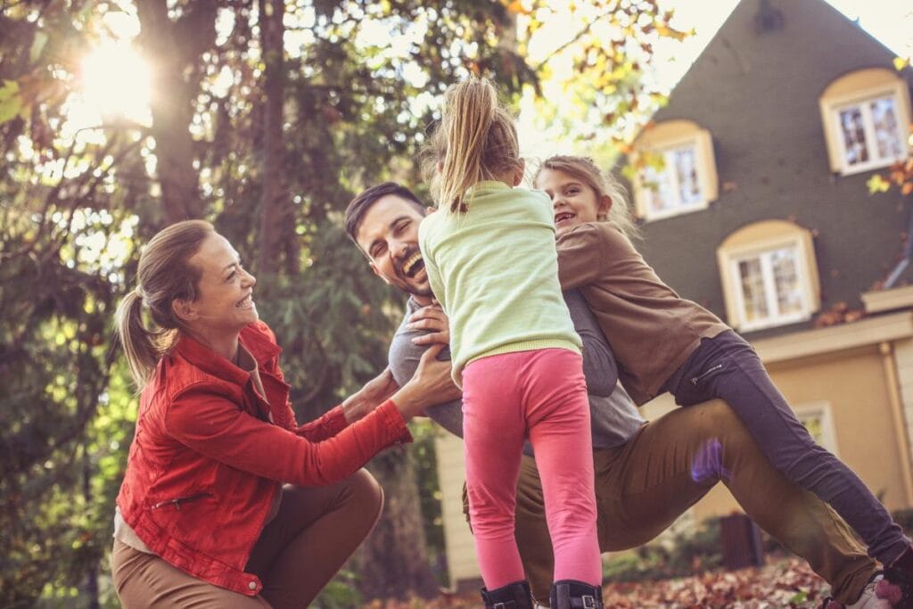 family of 4 in the backyard playing together in the autumn