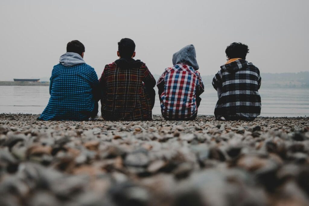 boys in flannel shirts sitting on a pebble beach