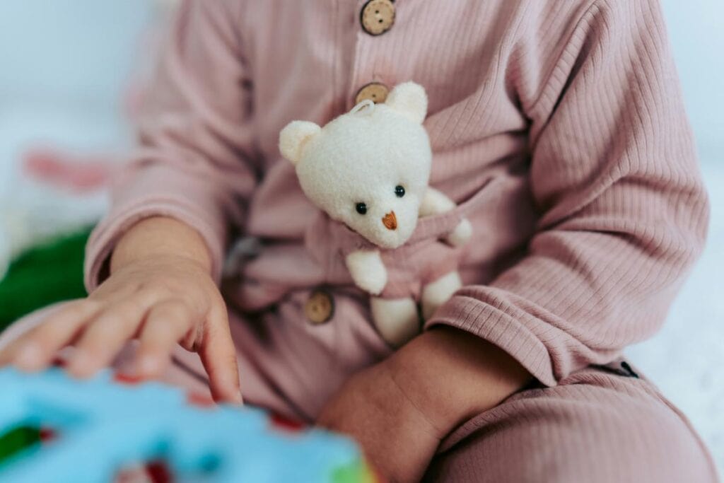 small child with tiny plush bear in pajama pocket