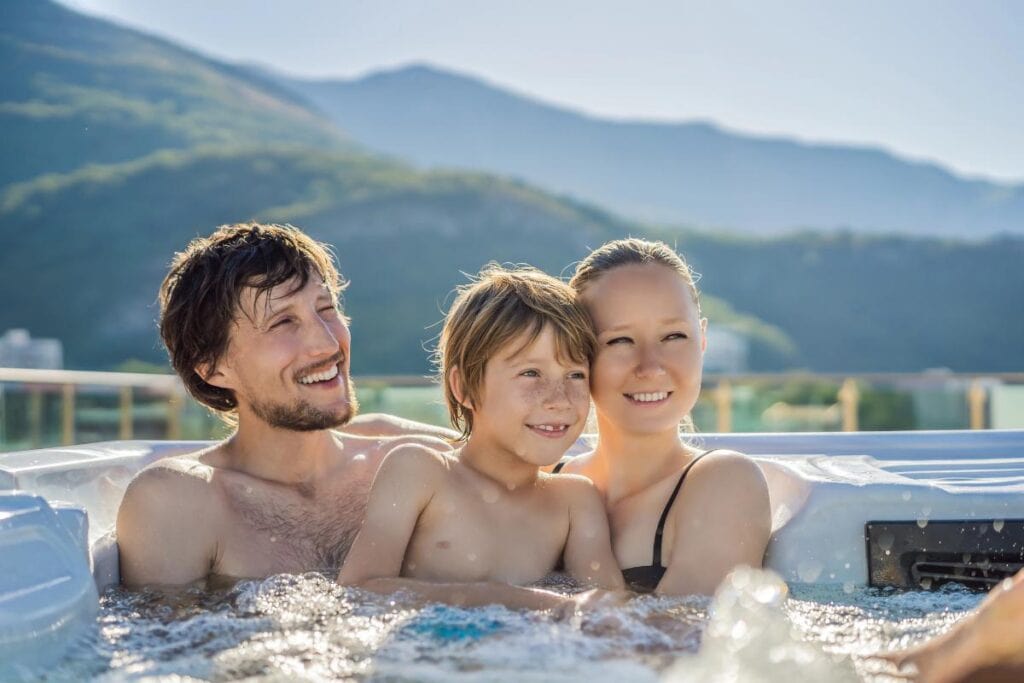a family in a hot tub with mountains in the background