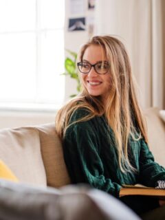 young woman in green sweater studying on a couch