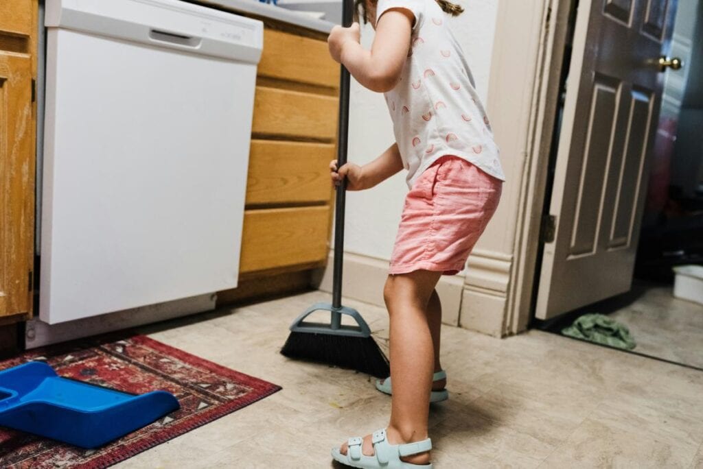 girl sweeping the kitchen floors to help with the household chores