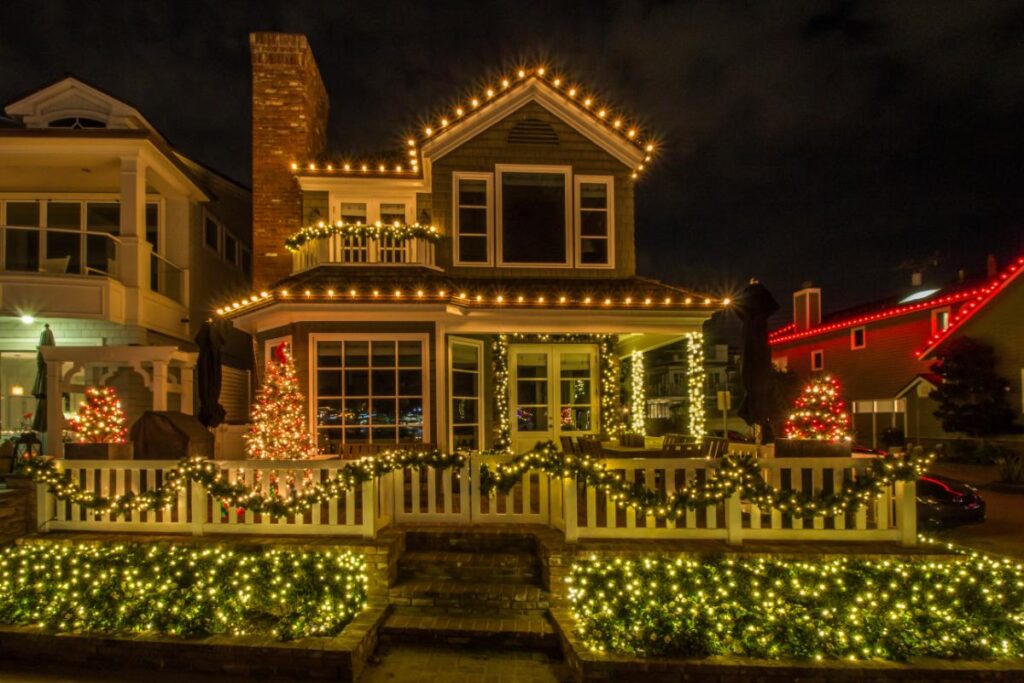 A beautifully decorated home with warm white Christmas lights outlining the roof, porch, and landscaping, showcasing professional holiday lighting installation.