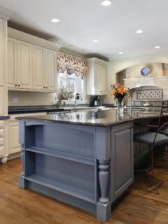 Elegant kitchen design with white cabinets, blue island, hardwood floors, and recessed lighting, creating an inviting open-concept space.