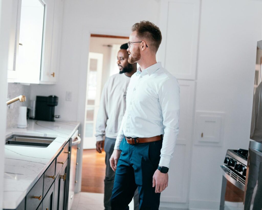 A landlord and tenant inspecting a modern kitchen with marble countertops and stainless steel appliances during a rental property walkthrough.