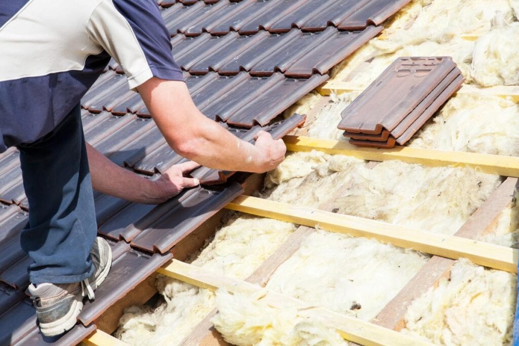 man installing and layering roof tiles