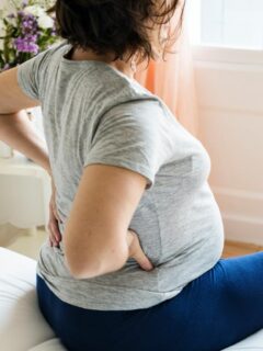 pregnant woman holding back - and often back pain persists post-partum