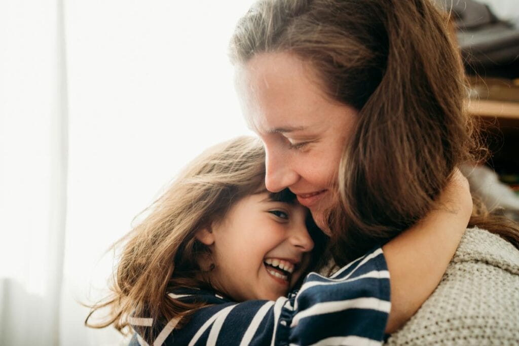 Close-up of a joyful hug between mother and daughter, both smiling warmly, capturing their special bond.