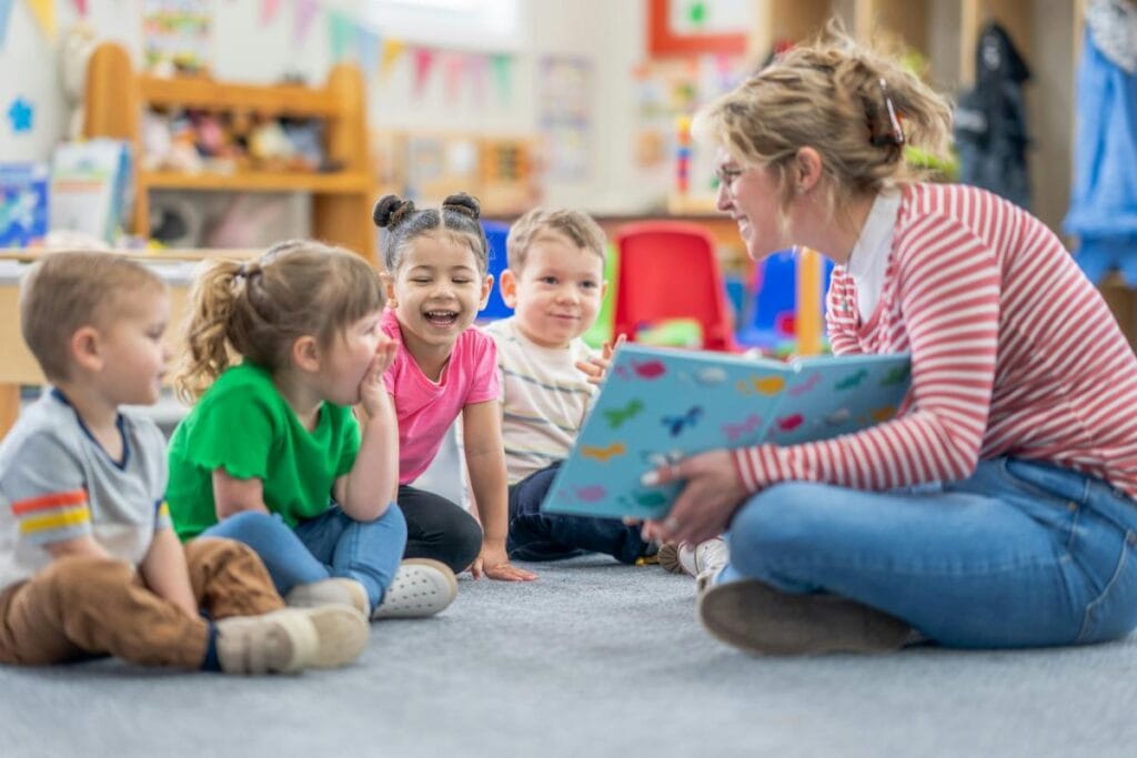 a preschool teacher sitting on the floor reading to her students