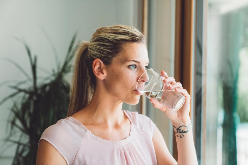 woman drinking water to wash down her morning supplements
