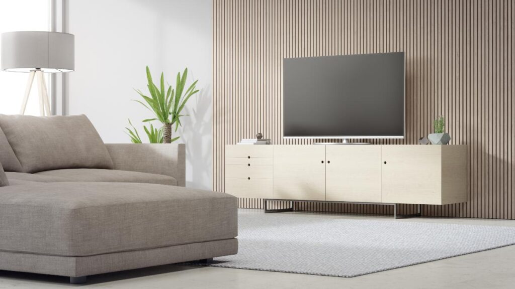Modern living room with a minimalist TV cabinet in light wood finish, paired with a wall-mounted TV, neutral sectional sofa, indoor plants, and soft lighting.