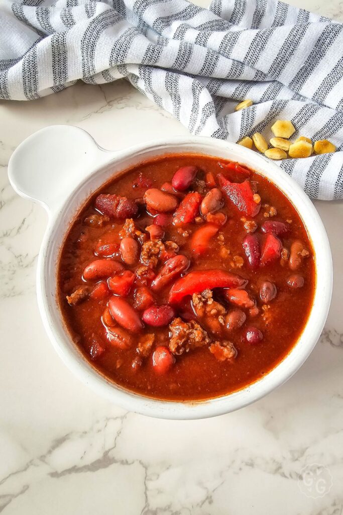 overhead shot of chili made with venison in a white bowl on marble background