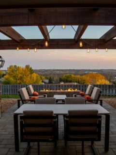 a patio with a pergola and fire pit near dusk