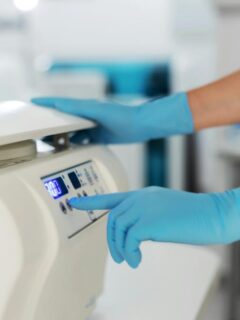 Medical professional in blue gloves operating a laboratory centrifuge, preparing samples for further drug screening or diagnostic testing.