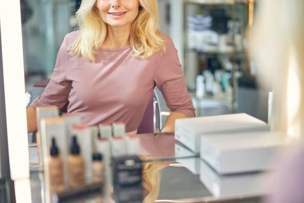 blonde woman in mauve dress at makeup counter