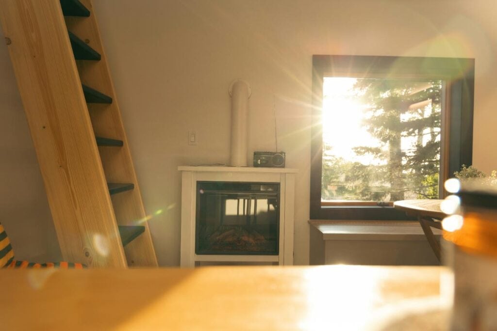 Cozy living room with sunlight streaming through a window, showing natural ventilation and warmth.