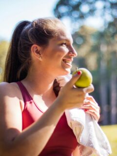 a woman eating an apple after her workout outdoors