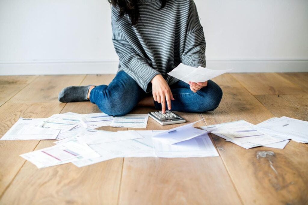 a woman sitting on the floor surrounded by bills